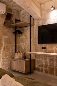 a room with a tv on a stone wall at Zekka House in Valletta +26 photos