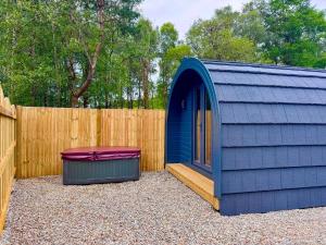 a blue shed with a bench next to a fence at 60 Mile Inn - Luxury Pods with Hot Tubs in Bridge of Orchy