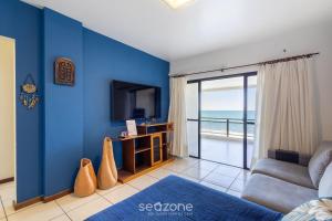 a living room with a tv and a blue wall at Apto Beira-Mar c/ Vista p/ Praia VTE0301 in Meia Praia