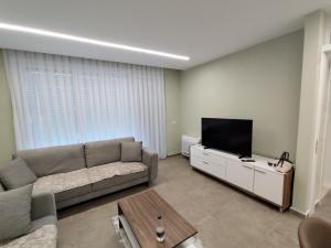 a living room with a couch and a flat screen tv at Green 2-bedroom apartment beach in Tale