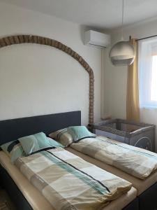 a large bed in a bedroom with a large headboard at Apartman - Garden - Vendégház 2 in Nesvady