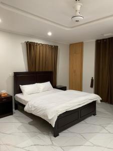 2-Bedroom Apartment near Islamabad International Airport Free Airport Pick and Drop في اسلام اباد: غرفة نوم بسرير كبير مع ملاءات بيضاء