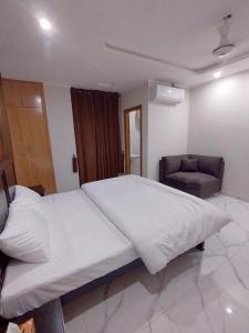 2-Bedroom Apartment near Islamabad International Airport Free Airport Pick and Drop في اسلام اباد: غرفة نوم بها سرير أبيض كبير وكرسي +6 صور