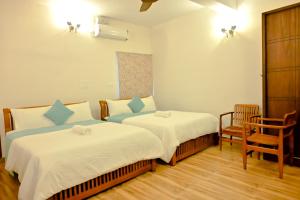 a hotel room with two beds and a chair at Villa Vaasa Luxury Homestay in Avathi