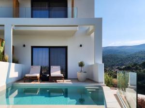 a house with a swimming pool and two chairs at Orizontas Suites in Syvota