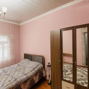 a bedroom with pink walls and a bed and a mirror at Warm Welcome Ivanovka in İvanovka +11 photos