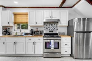 a kitchen with white cabinets and a stove top oven at 2 Homes Retreat Game Rooms & Fire Pit Winni in Moultonborough
