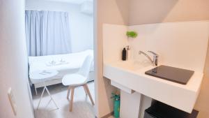 baño con lavabo blanco y silla blanca en 9stay蔵前, en Tokio