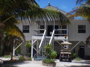 a white house with palm trees in front of it at Escape Away Belize Beach House in San Pedro