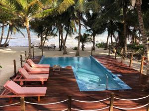 a swimming pool next to a beach with palm trees at Escape Away Belize Beach House in San Pedro