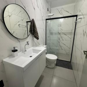 a white bathroom with a sink and a mirror at Casa Azul, Privativa, Confortável, AR, Wi-Fi in Joinville