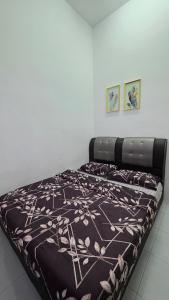 a bed with a brown and white blanket on it at Andalus Homestay in Jerantut