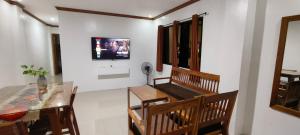 a dining room with a table and a television on a wall at Casa Victoria Pension House-Star Maria in Somosomo