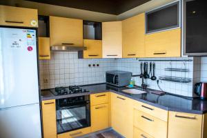 a kitchen with wooden cabinets and a white refrigerator at Doba In Ua Peremoga Apartments in Dnipro