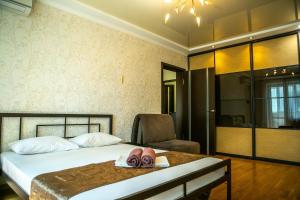a bedroom with a bed with a chair and two slippers at Doba In Ua Peremoga Apartments in Dnipro