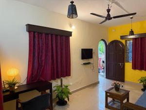 a living room with red curtains and a tv at Casa De Emilia in Anjuna