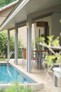 a patio with a pool and a table and chairs at 2 bedroom neer phuket airport in Nai Thon Beach