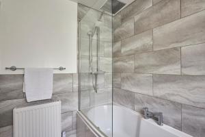 a bathroom with a bath tub and a shower at Vacant Nests The Park View Seaham Hideaway  +36 photos