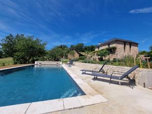 a swimming pool with two chairs and a house at Les Peyronnies in Figeac