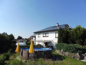 a house with a swimming pool and two umbrellas at 3 Sterne Gästehaus Zollerblick in Zimmern