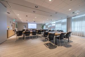 a conference room with tables and chairs and a screen at Crowne Plaza Utrecht - Central Station by IHG in Utrecht