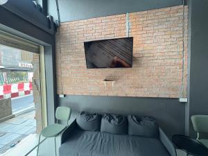 バンコクにあるNomad Yard Hostelのレンガの壁に掛けられたテレビとソファ +22枚の写真