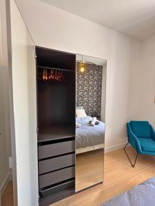 a bedroom with a mirror and a bed and a blue chair at Vue Odet - calme & lit Queen Size à Quimper in Quimper
