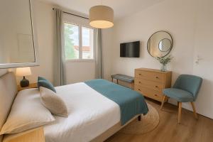 a bedroom with a bed and a chair and a mirror at Les prés de Prat in Noaillan