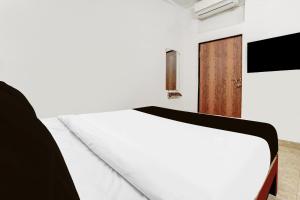 a bedroom with a white bed and a wooden door at Hotel O KPN Holiday Homes in Goa