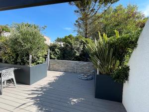 eine Terrasse mit Topfpflanzen, einem Tisch und einem Zaun in der Unterkunft "Maison de la mer" à 200 m de la plage - St Jean de Monts in Saint-Jean-de-Monts