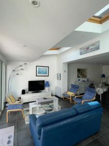 ein Wohnzimmer mit einem blauen Sofa und Stühlen in der Unterkunft "Maison de la mer" à 200 m de la plage - St Jean de Monts in Saint-Jean-de-Monts