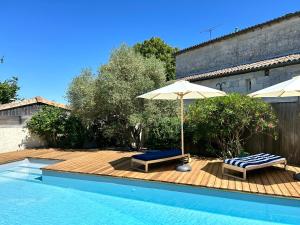 a swimming pool with two chairs and an umbrella at La Bohème in Galgon