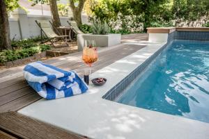 a glass of wine sitting next to a swimming pool at The Corner House L'A-nnexe in Franschhoek