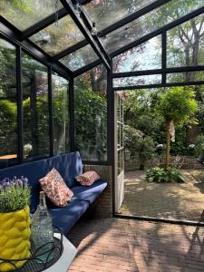 a conservatory with a blue couch and a glass door at B&B bij Germaine in Heeze