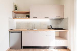 a kitchen with white cabinets and a sink at KYMA STAY - Beachfront apartments in Pálioura