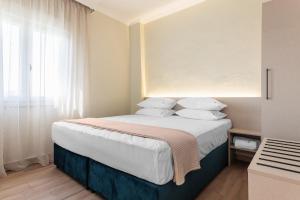 a bedroom with a bed with white sheets and pillows at KYMA STAY - Beachfront apartments in Pálioura
