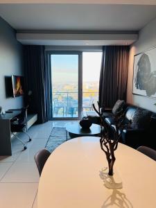 a living room with a table and a large window at Sandton Pool View with Balcony in Johannesburg
