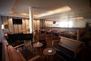 a restaurant with a piano and a bar with tables at Waldhotel Stuttgart in Stuttgart