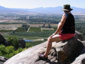una donna seduta su una roccia che guarda la valle di Rhodene Farm Cottages a Prince Alfreds Hamlet