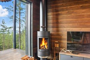 a fireplace in a cabin with a view of the woods at Villa Pikku Karhu in Kuusamo