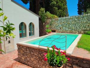 a swimming pool in a backyard with a stone wall at Villa Miami Taormina in Taormina
