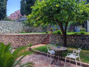 a patio with a table and chairs under a tree at Villa Miami Taormina in Taormina