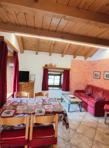 een woonkamer met een tafel en een rode bank bij PiZABELA MANSARDE in Livigno