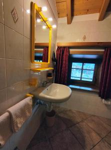 een badkamer met een wastafel, een spiegel en een raam bij PiZABELA MANSARDE in Livigno +23 foto's