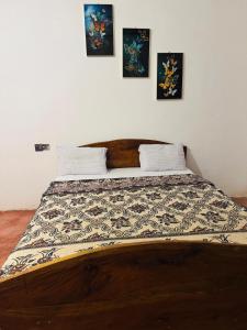 een bed in een slaapkamer met drie foto's aan de muur bij Won Happy Hotel - Kitulgala in Kitulgala