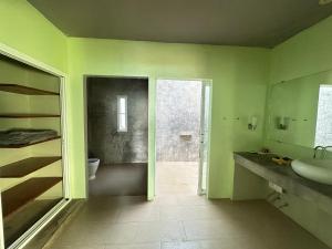 a green bathroom with a sink and a toilet at KohMakHomeHug Resort in Ko Mak