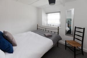 a bedroom with a bed and a chair and a mirror at Hurst Cottage - A Cosy 2-Bedroom Cottage Escape in Dorset in Stalbridge