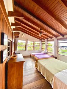 une chambre avec deux lits dans une pièce avec fenêtres dans l'établissement Vila Costa Sul Chalés e Estúdios, à Ilhabela