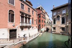 two people standing on a balcony next to a canal at Anzolo Palace - Rooms & Apartments in Venice