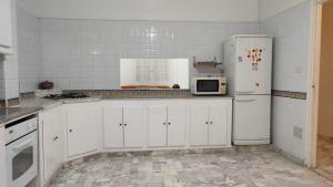 a white kitchen with a refrigerator and a microwave at Villa avec piscine au style Sibi Bou Saïd in Sousse